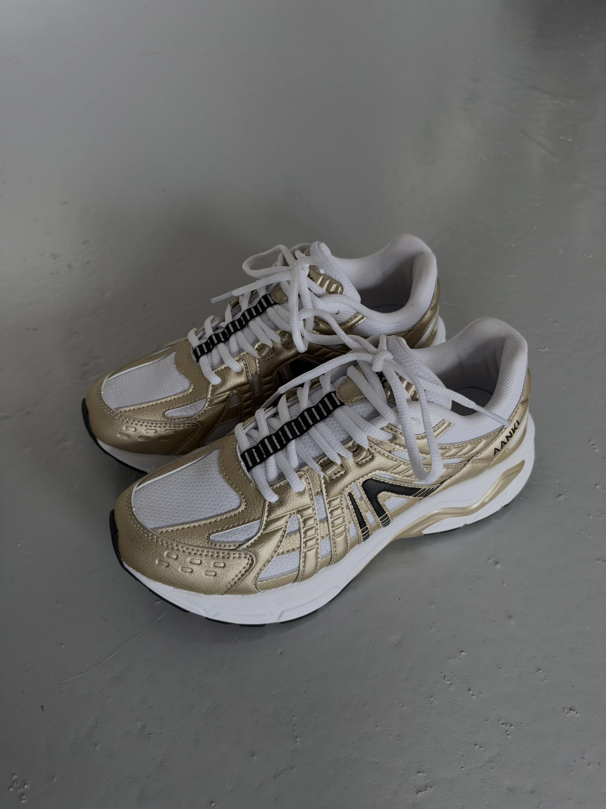 AANKL GLIDE Gold/White – originalfoto af skoene på gråt gulv